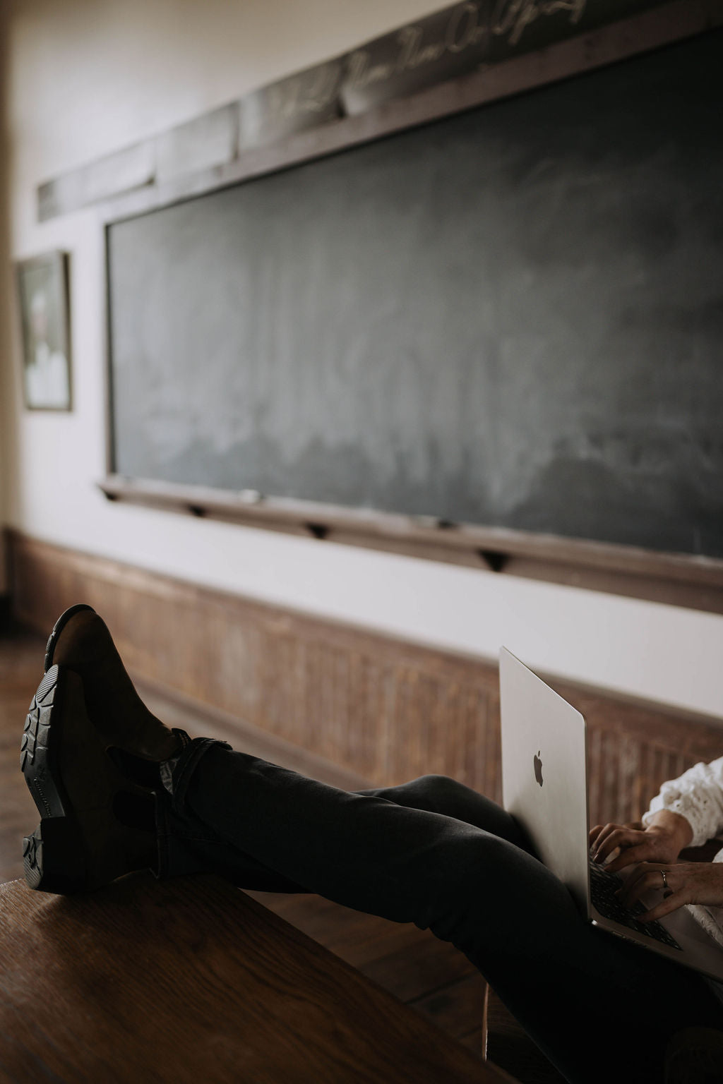 Person using a laptop on the floor in front of a chalkboard